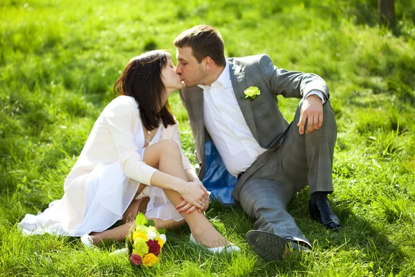 Acabou de se casar em um jardim florido sentado na grama — Fotografia de Stock