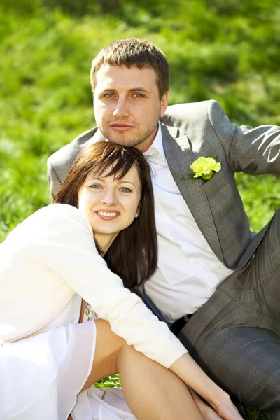 Just married in a flowering garden sitting on the grass — Stock Photo, Image