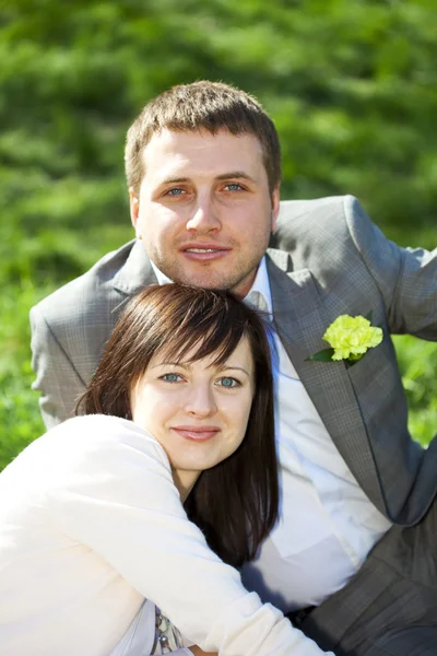 Только что поженились в цветочном саду, сидя на траве — стоковое фото