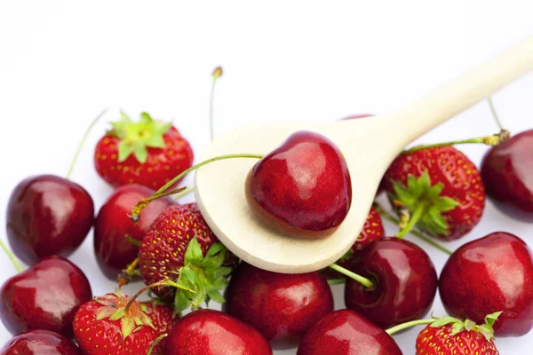 Cherry en aardbei in een houten lepel geïsoleerd op wit — Stockfoto