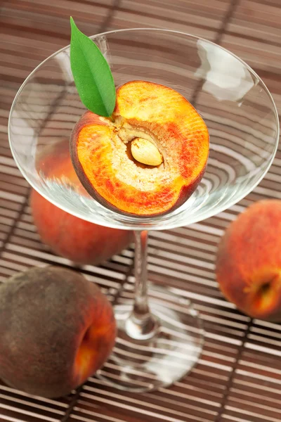 Персик в бокале мартини на бамбуковом коврике — стоковое фото