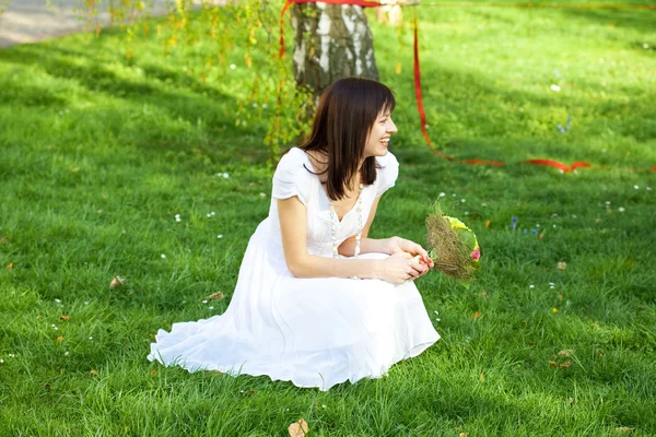 Novia con un ramo sentado en la hierba — Foto de Stock