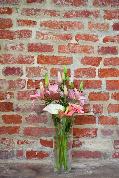 Flowers in a vase standing in the background of a brick wall — Stock Photo, Image
