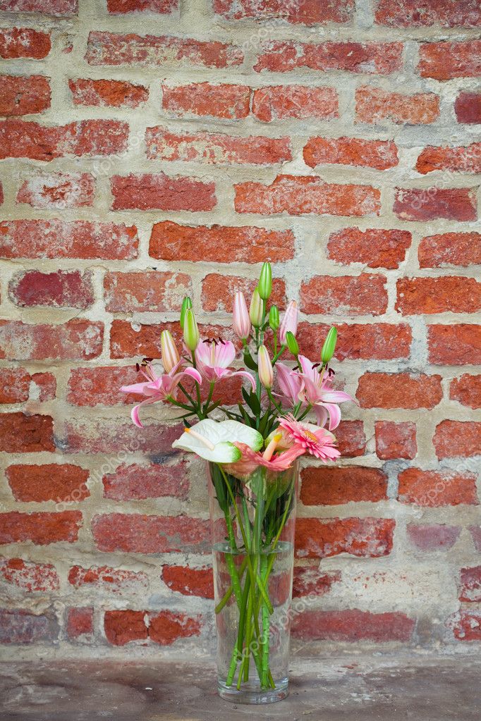 Flowers in a vase standing in the background of a brick wall — Stock
