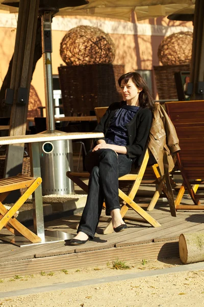 Ung kvinna sitter vid ett bord i ett café — Stockfoto