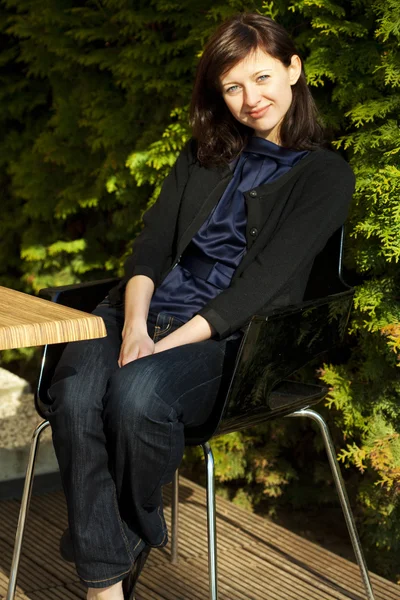 Jovem mulher sentada a uma mesa em um café — Fotografia de Stock