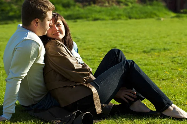 Молодая пара, сидящая на зеленой траве — стоковое фото