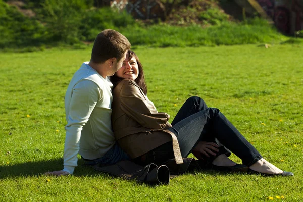 Jovem casal sentado na grama verde — Fotografia de Stock