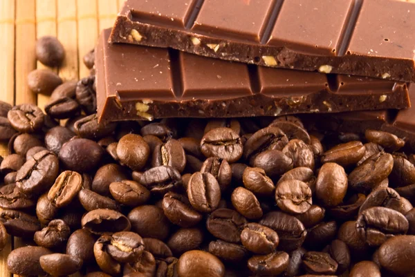 stock image A bar of chocolate and coffee beans lying on a bamboo mat