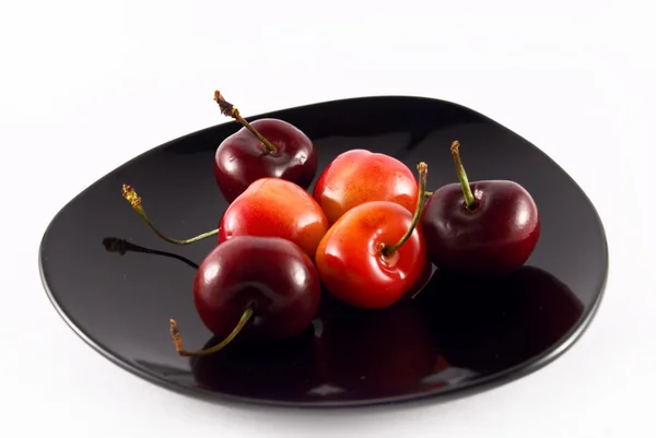 Cherry on a black plate isolated on white — Stock Photo, Image