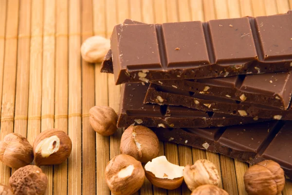Chocolate and nuts on a bamboo mat — Stock Photo, Image