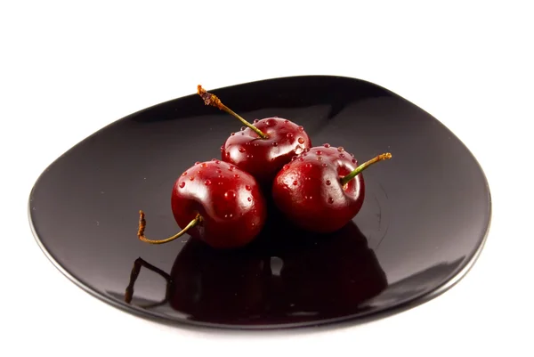 Cherries on a black saucer isolated on white — Stock Photo, Image