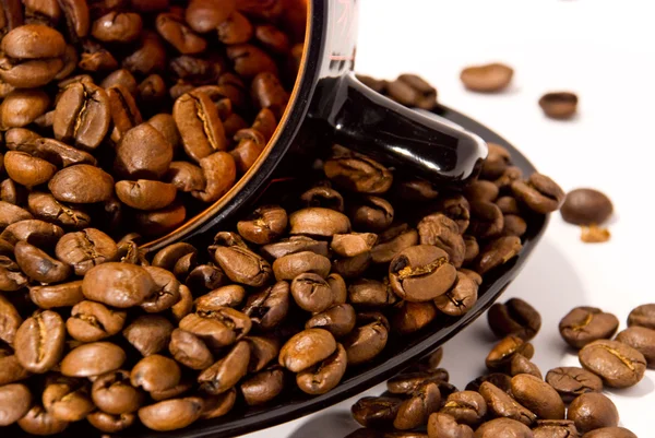 Kop en schotel met de bonen van de koffie geïsoleerd op wit — Stockfoto