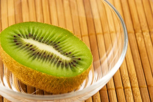 Kiwi fruta em uma tigela de vidro em uma esteira de bambu — Fotografia de Stock