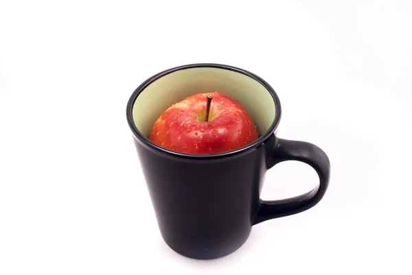 Яблоко в чашке, изолированной на белом — стоковое фото