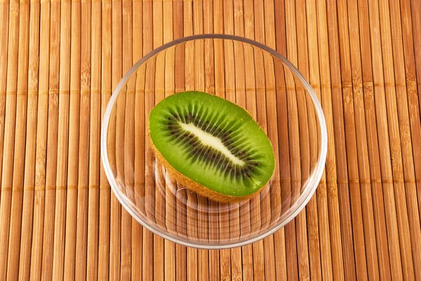 Kiwi en un tazón de vidrio en una estera de bambú — Foto de Stock