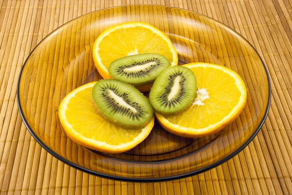 Kiwi fruit and oranges on a plate — Stock Photo, Image
