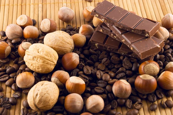 Nuts and chocolate on a bamboo mat — Stock Photo, Image