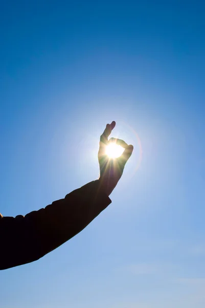 该名男子手持一个太阳在他的手对着天空 — 图库照片
