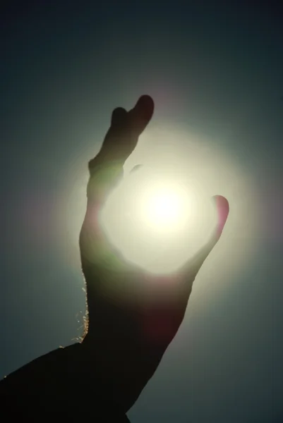 Homem segurando um sol em suas mãos contra o céu — Fotografia de Stock