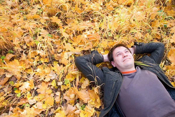 Retrato de un hombre acostado sobre hojas de otoño — Foto de Stock