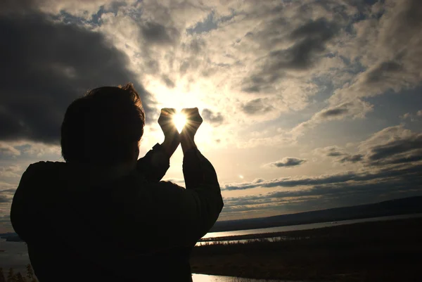 Hombre sosteniendo un sol en sus manos contra el cielo —  Fotos de Stock