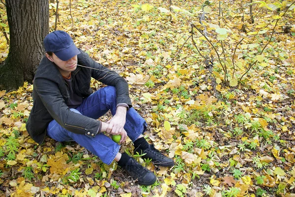 Человек, сидящий в осеннем лесу — стоковое фото