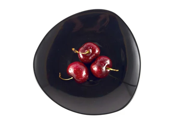 Cherry on a black plate isolated on white — Stock Photo, Image