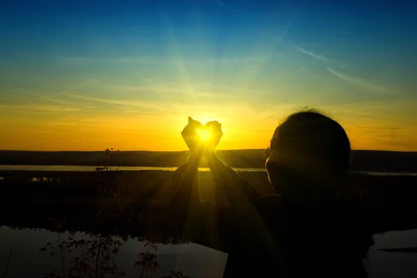 Kvinna anläggning solen i händerna — Stockfoto