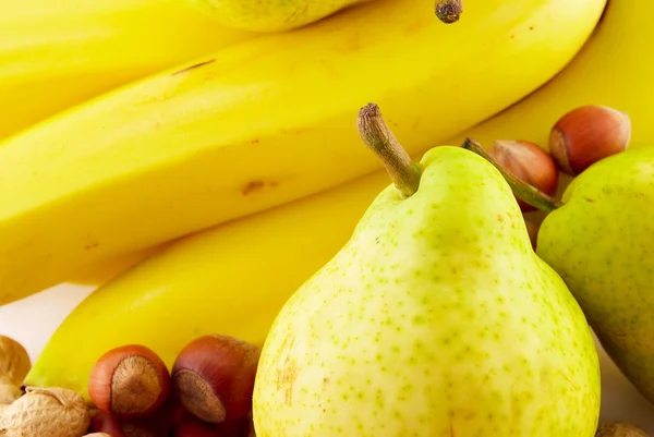 Бананы, груши и орехи на белом фоне — стоковое фото