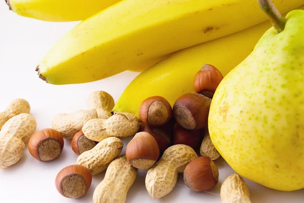 Бананы, груши и орехи на белом фоне — стоковое фото