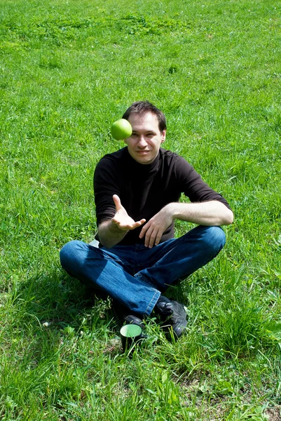 Człowiek siedzi na zielonej trawie — Zdjęcie stockowe