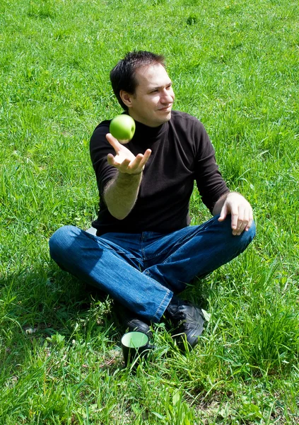Человек, сидящий на зеленой траве — стоковое фото