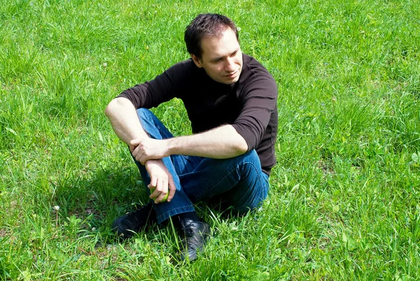 Homem sentado na grama verde — Fotografia de Stock