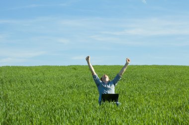 Young man using laptop in the field clipart