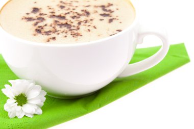 fincan cappuccino ve yeşil bir bez üzerinde beyaz bir çiçek