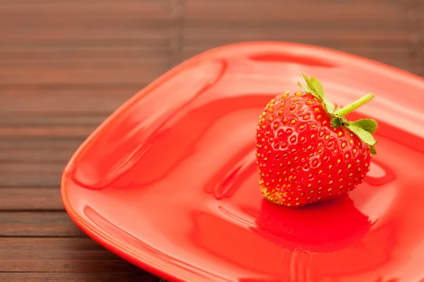 Erdbeeren und ein Teller auf einer Bambusmatte — Stockfoto