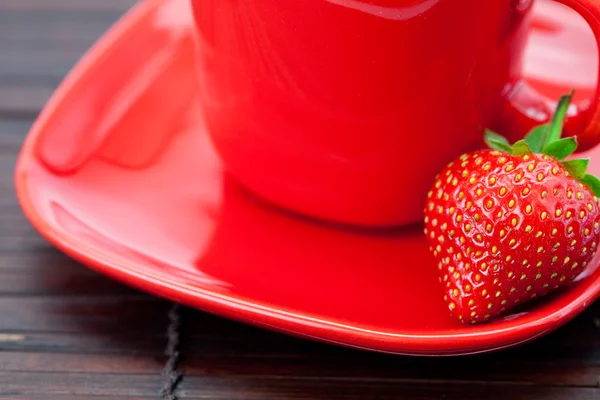 Cup and saucer and strawberries on a bamboo mat — Stock Photo, Image