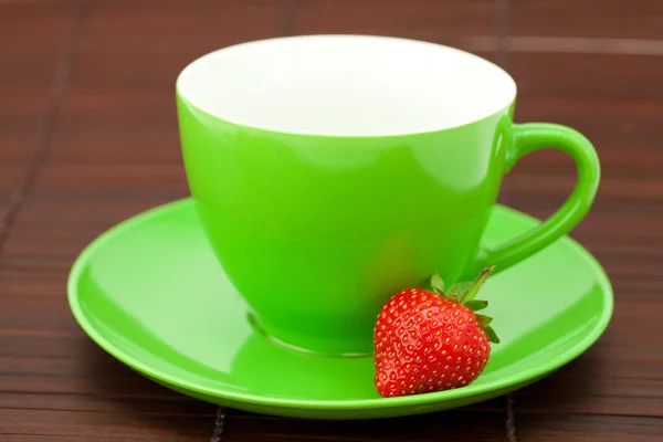 Tasse mit Untertasse und Erdbeeren auf einer Bambusmatte — Stockfoto