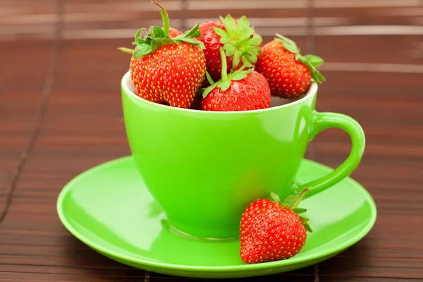 Cup and saucer and strawberries on a bamboo mat — Stock Photo, Image