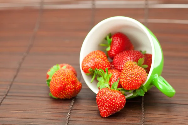 Cup and strawberries on a bamboo mat — Stock Photo, Image