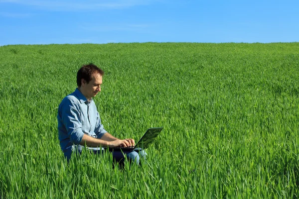 Jovem usando laptop no campo — Fotografia de Stock