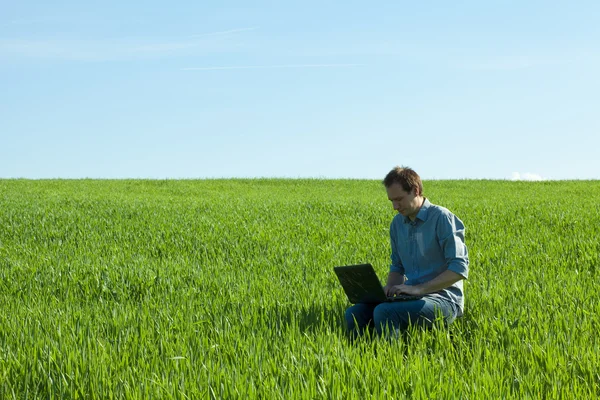 Jeune homme utilisant un ordinateur portable sur le terrain — Photo