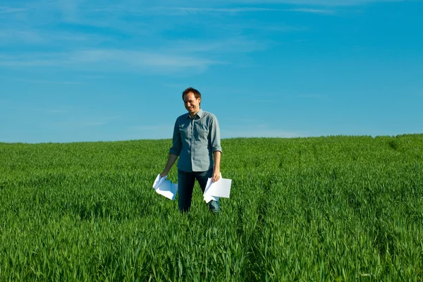 Jeune homme jetant un papier dans le champ vert — Photo