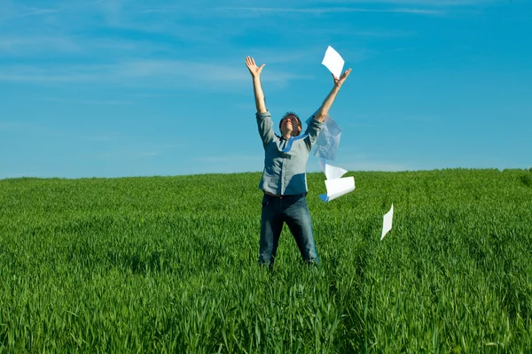 Ung man kastar ett papper i det gröna fältet — Stockfoto