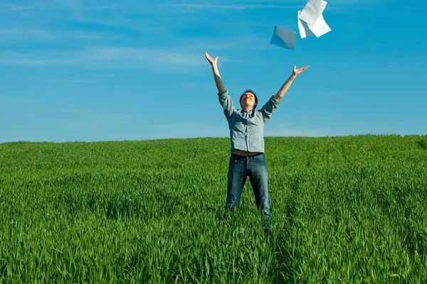 Jonge man een papier gooien in het groene veld — Stockfoto