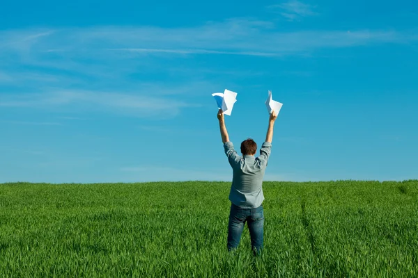 Jonge man een papier gooien in het groene veld — Stockfoto