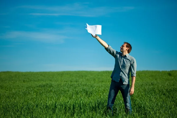 Ung man kastar ett papper i det gröna fältet — Stockfoto