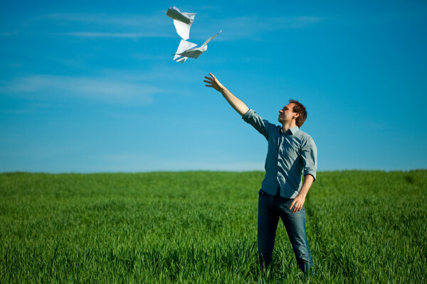 Young man throwing a paper in the green field
