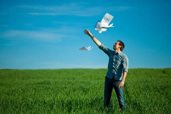 Молодой человек бросил бумагу в зеленое поле — стоковое фото